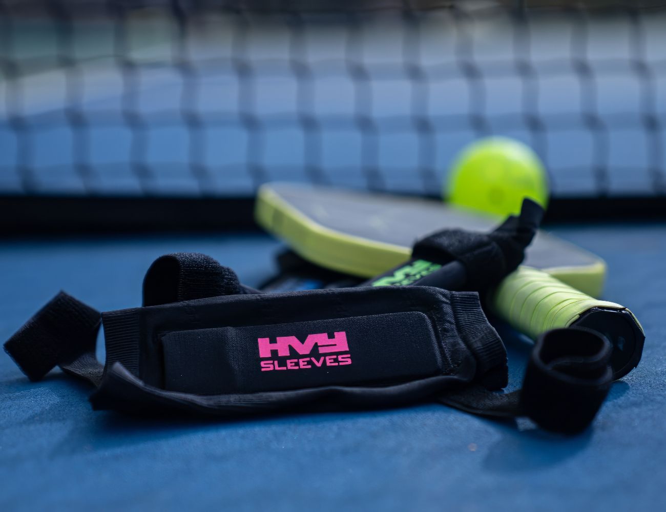 HVY SLeeves sitting on a pickleball court next to a pickleball and paddle