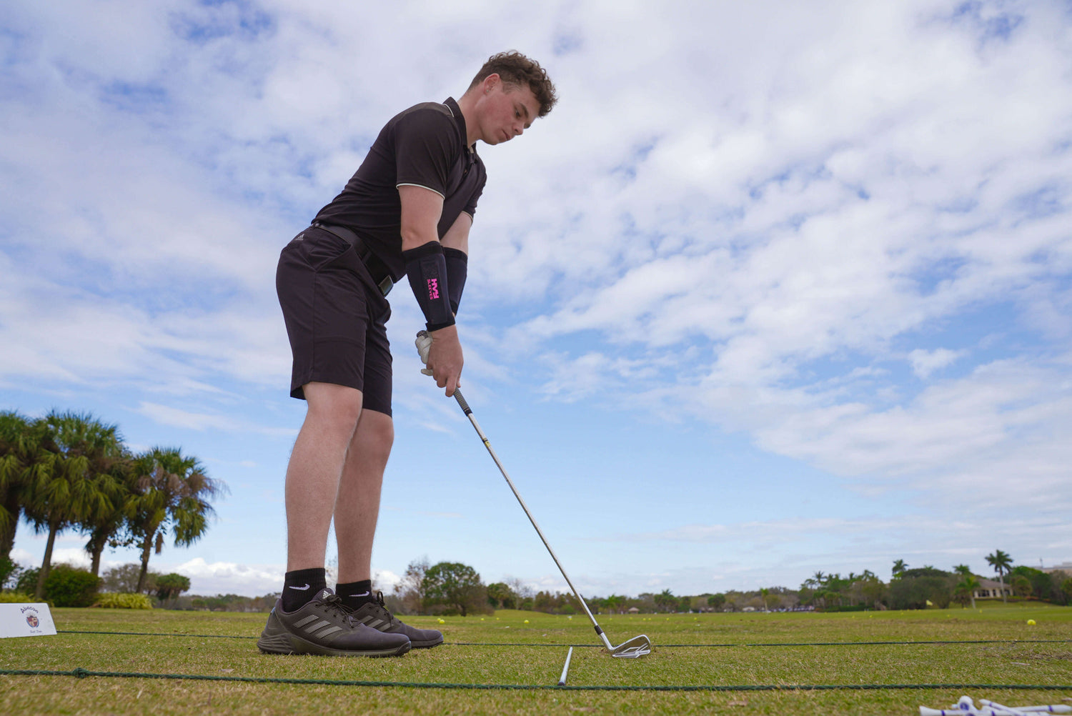 a golfer getting ready to swing his club while wearing wrist weights.