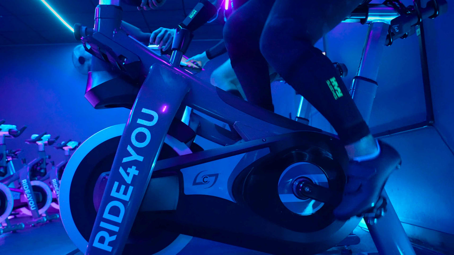 A cyclist on an indoor training bike wearing HVY sleeves on their legs and arms