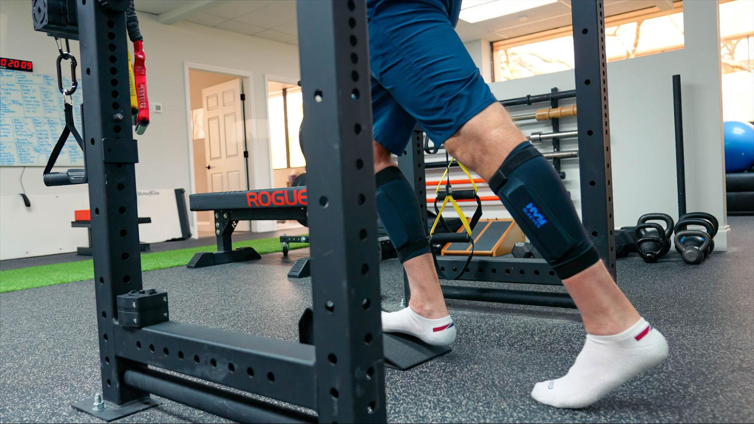 a man in a squat rack with ankle weights on